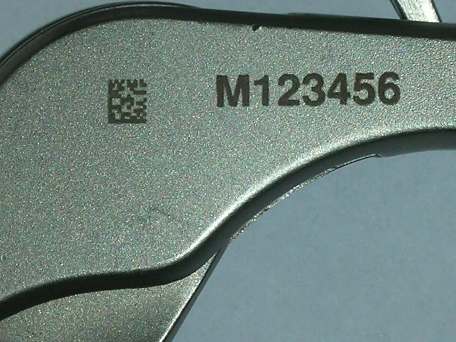 Data matrix code and serial number M123456 laser-etched onto a metallic surface