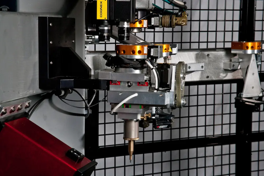 Industrial machinery with a precision dispenser tool and Cognex camera system mounted on a mechanical arm
