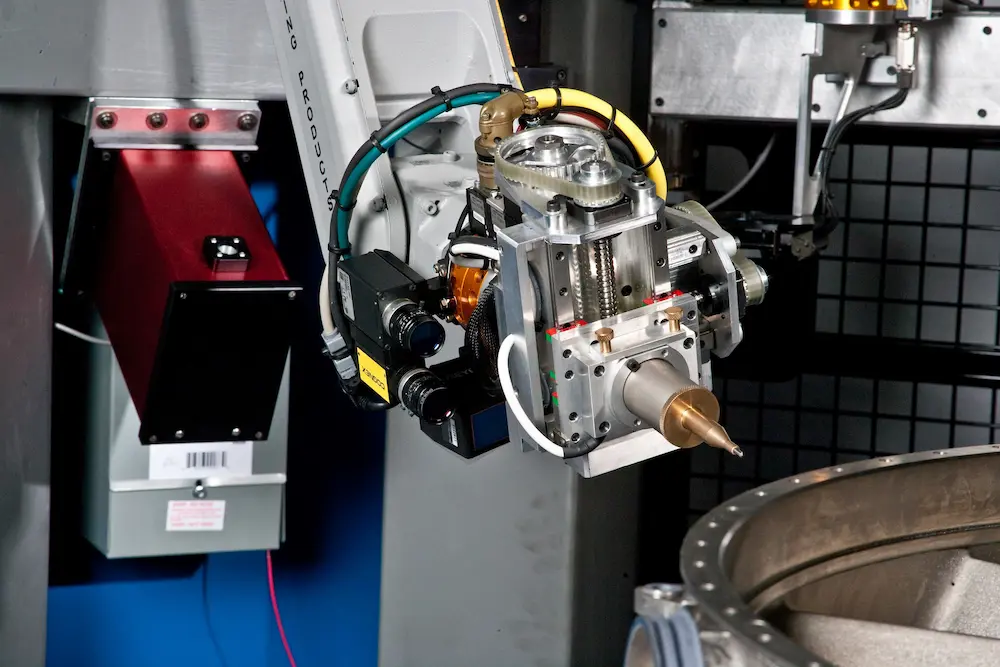 Robotic arm and precision machining tool positioned above a metallic component