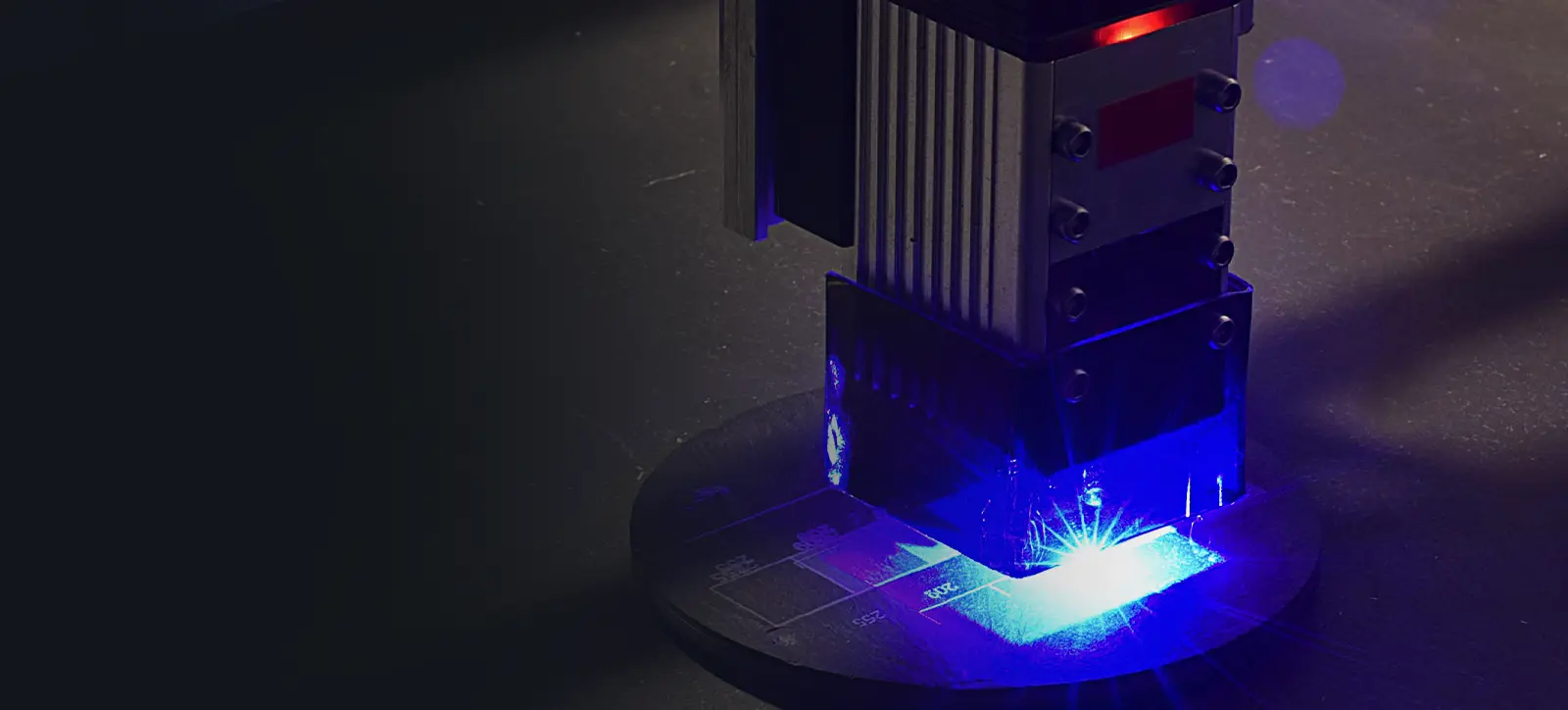 A laser engraver with a bright blue light etching a circular metal plate