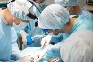 A team of surgeons in scrubs, masks, and caps performing an operation